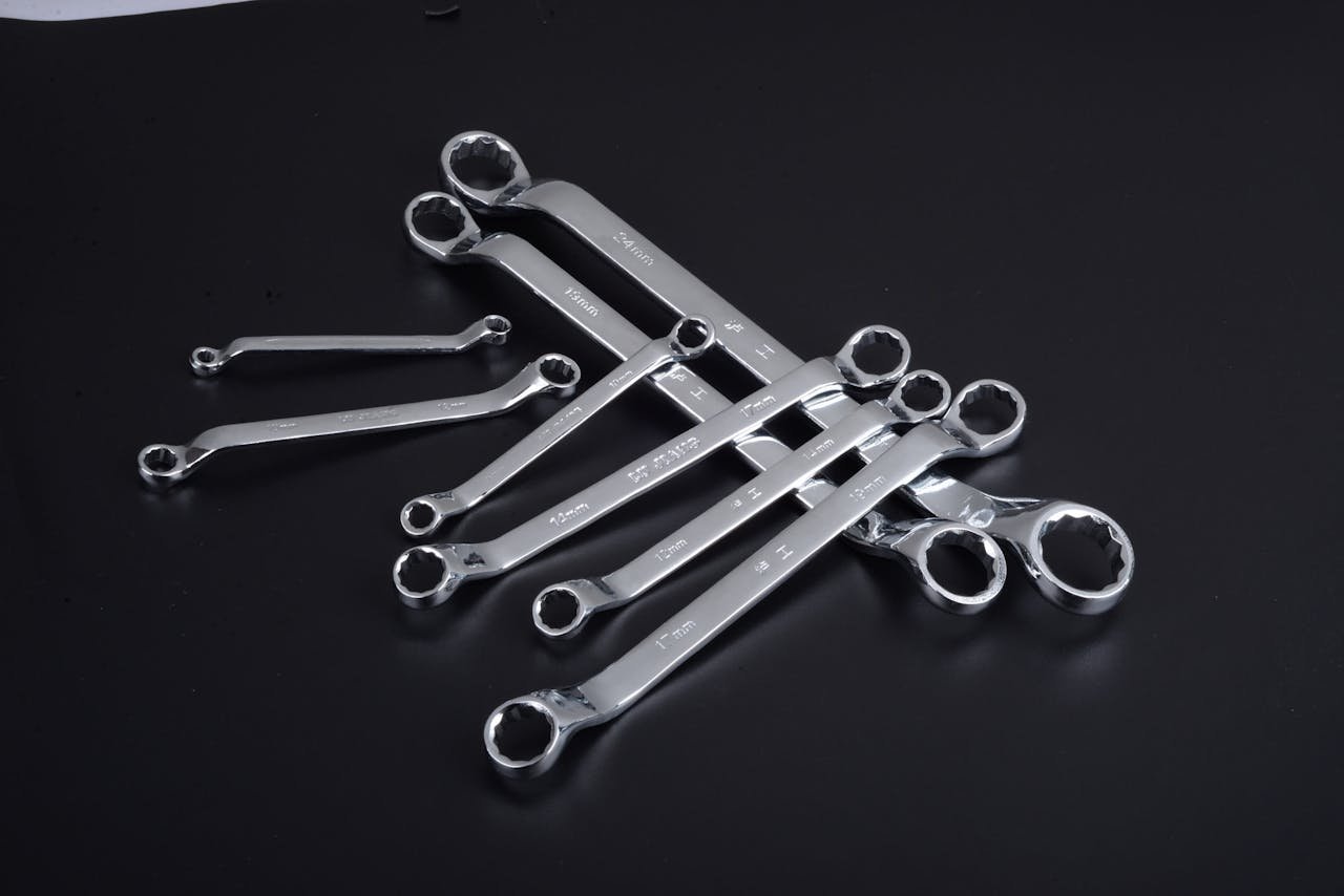 A set of shiny chrome wrenches arranged on a sleek black background, perfect for tool enthusiasts.